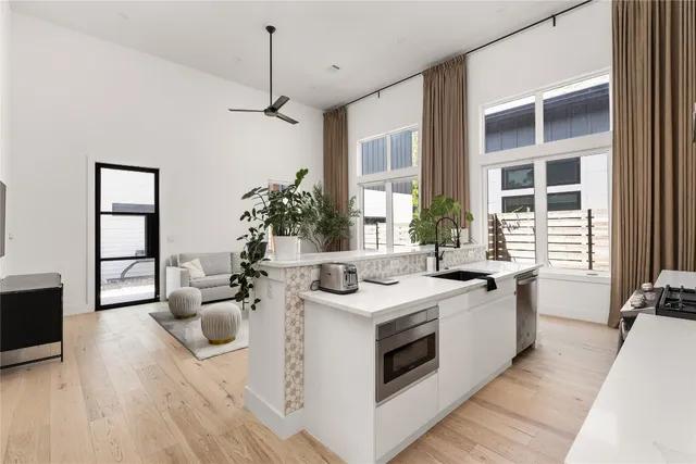 a kitchen that has a sink and a stove with wooden floor
