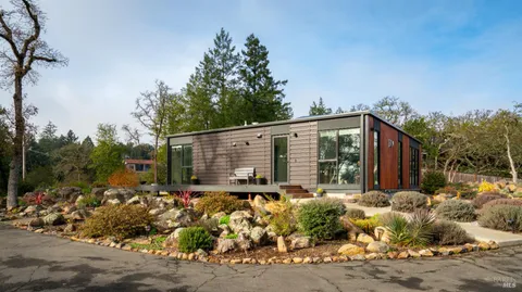 a backyard of a house with large trees and outdoor seating