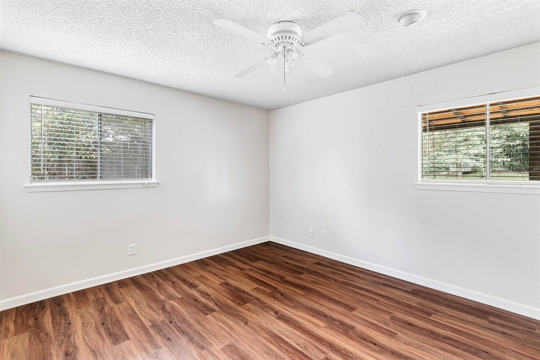7506 Glenhill Road Austin, TX 78752 - Photo 14 of 24 Wood-like floors and generous windows elevate this serene, naturally illuminated bedroom.