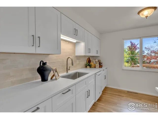 a kitchen with a sink dishwasher and cabinets with wooden floor