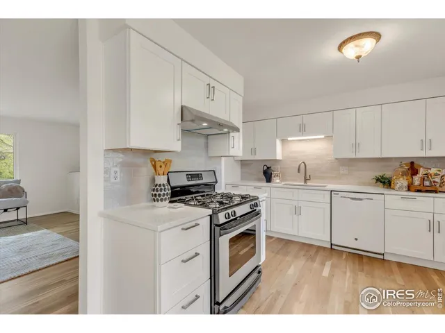 a kitchen with stainless steel appliances granite countertop a stove a sink and white cabinets