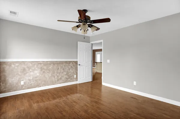 an empty room with wooden floor and windows with curtains