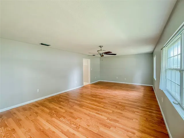 a view of empty room with wooden floor and fan