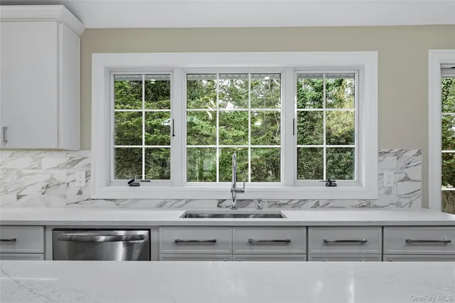 a view of kitchen with granite countertop a sink and a window