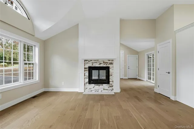 an empty room with wooden floor fireplace and windows