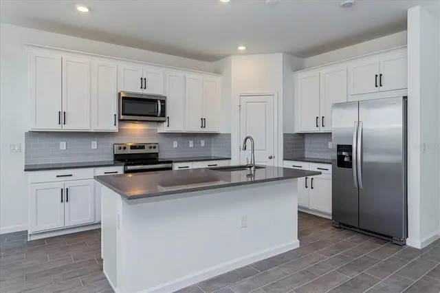 a kitchen with stainless steel appliances granite countertop a sink stove microwave and refrigerator