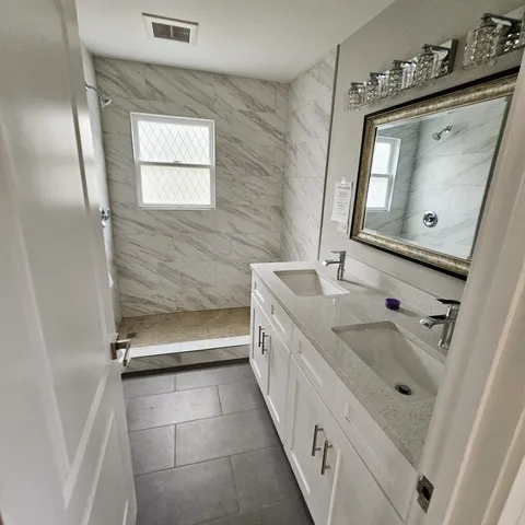 a bathroom with a double vanity sink mirror and bathtub