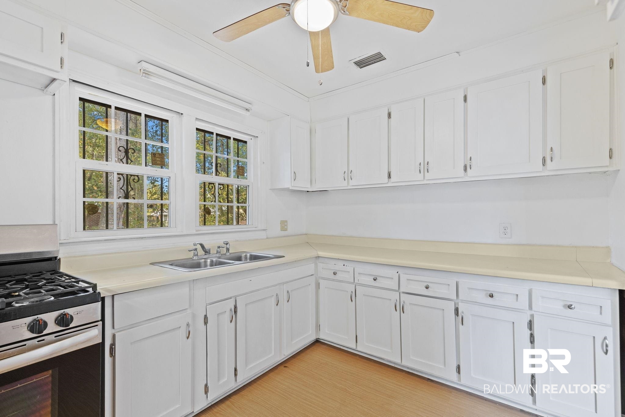1665 Johnston Street Mobile, AL 36605 - Photo 8 of 17 Kitchen featuring gas range, white cabinetry, sink, crown molding, and light hardwood / wood-style floors