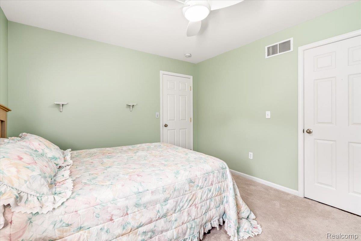 49105 Hawksburry Road Canton, MI 48188 - Photo 30 of 51 Bedroom featuring light green walls, beige carpeting, two white paneled doors, and a ceiling fan with integrated lighting