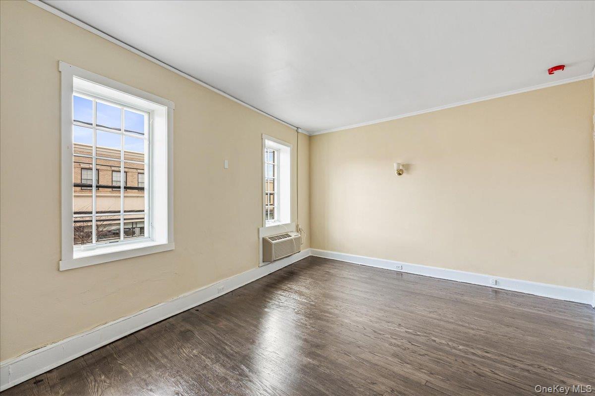 409 Plandome Road, Unit H Manhasset, NY 11030 - Photo 5 of 15 an empty room with wooden floor and windows