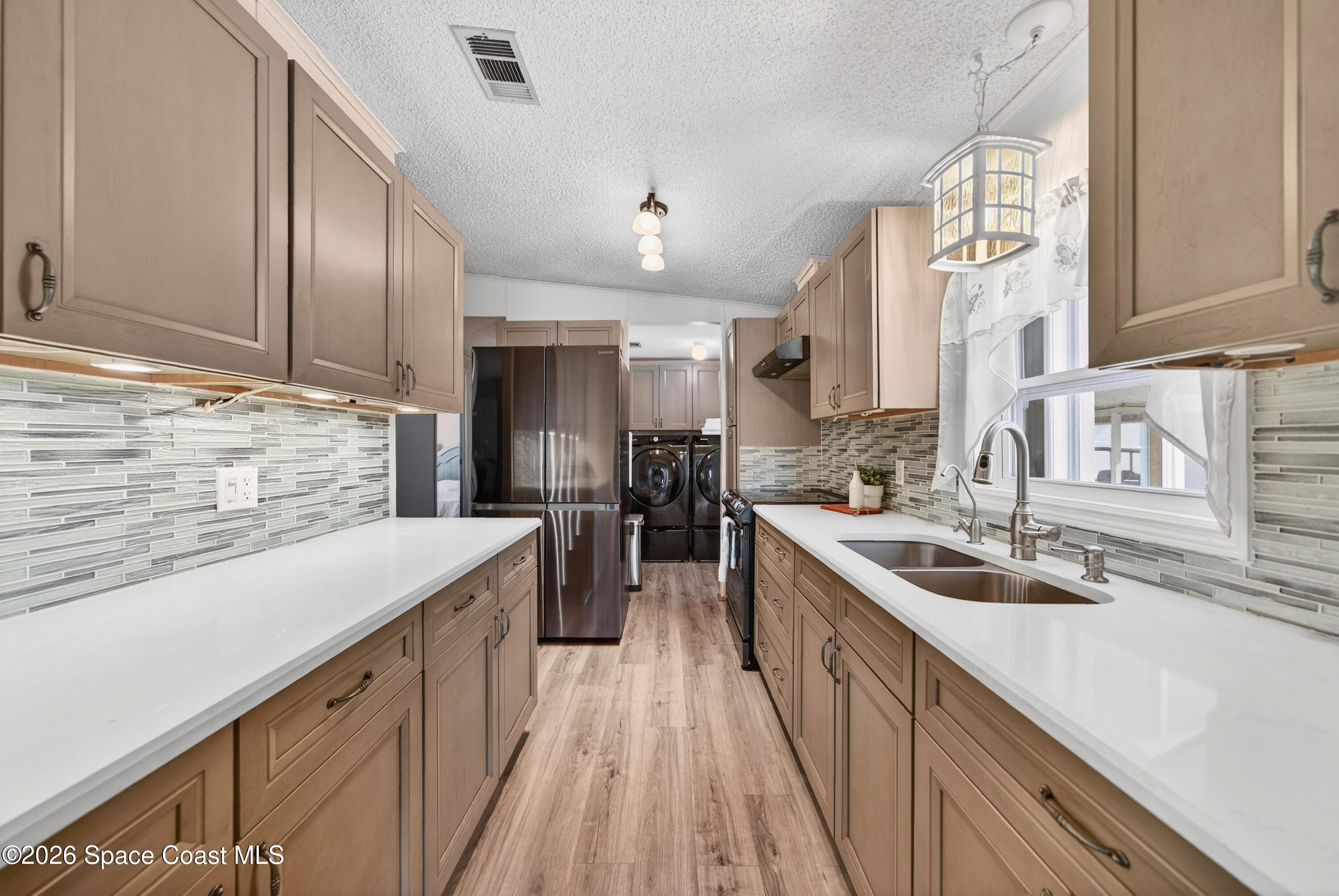 7645 Chasta Road Micco, FL 32976 - Photo 7 of 39 a kitchen with a sink stove cabinets and wooden floor