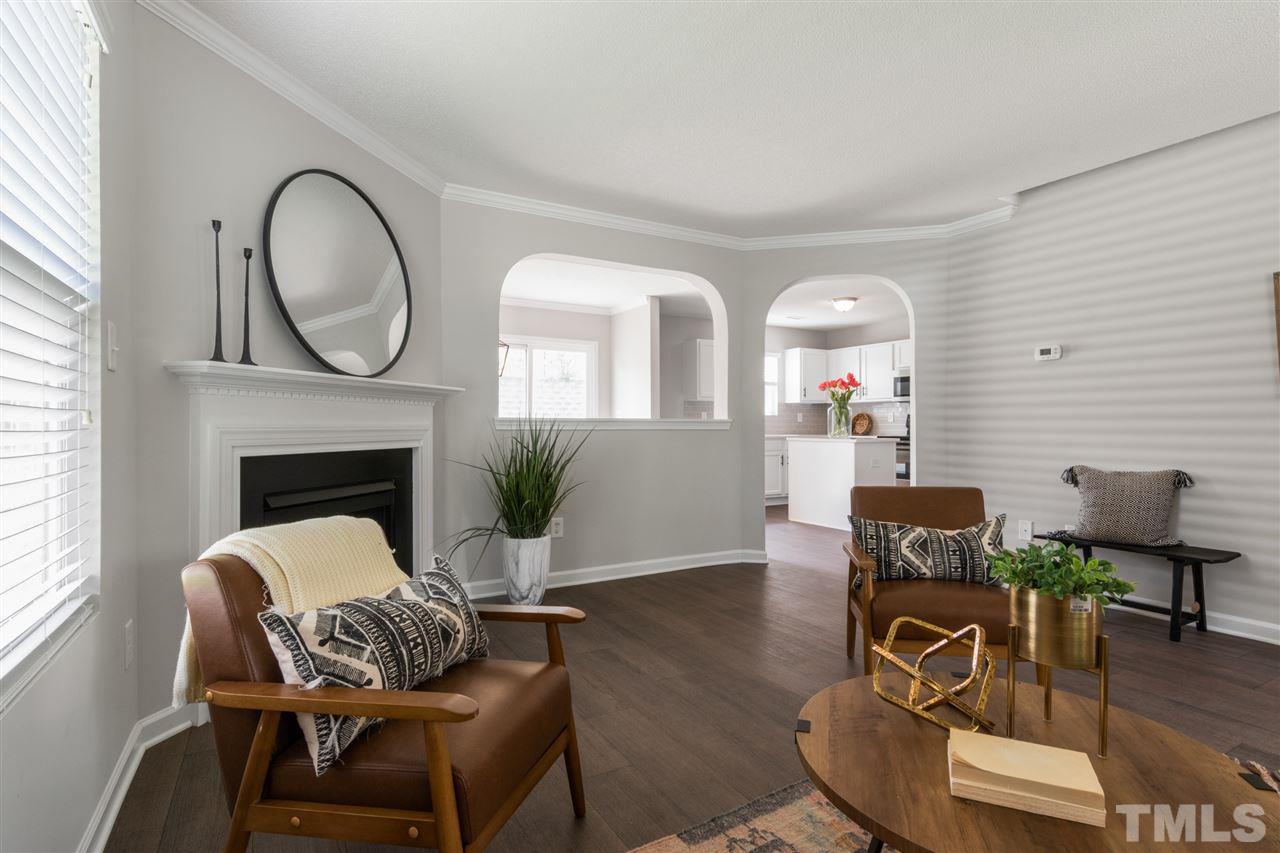 6852 Harter Court Raleigh, NC 27610 - Photo 5 of 29 a living room with furniture a table a fireplace and a large window