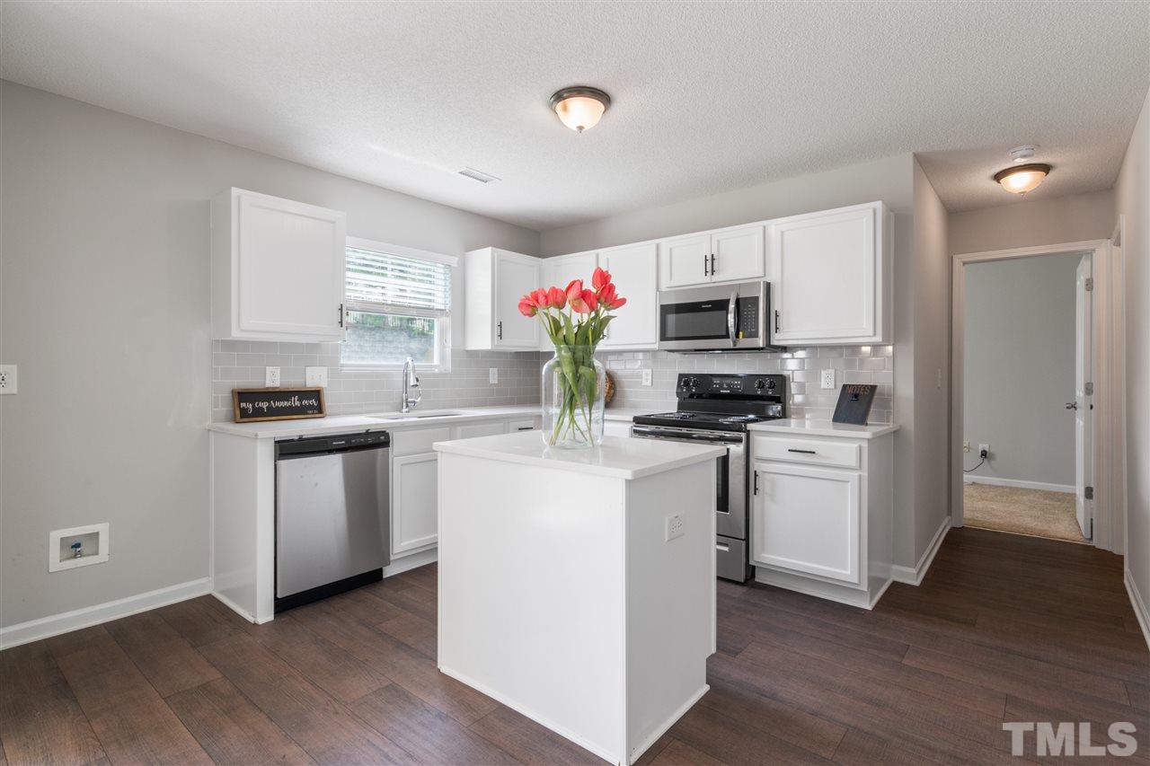 6852 Harter Court Raleigh, NC 27610 - Photo 6 of 29 a kitchen with kitchen island granite countertop stainless steel appliances a stove top oven a sink and dishwasher with wooden floor