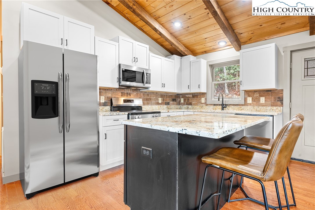 214 Ridge Run Road West Jefferson, NC 28694 - Photo 9 of 49 a kitchen with stainless steel appliances granite countertop a refrigerator a stove a sink a dining table and chairs with wooden floor