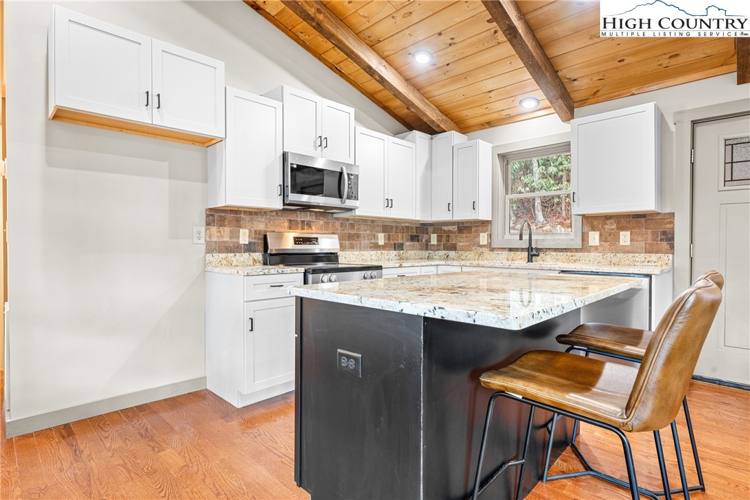 214 Ridge Run Road West Jefferson, NC 28694 - Photo 10 of 49 a kitchen with stainless steel appliances granite countertop a stove a sink dishwasher and a refrigerator with wooden floor