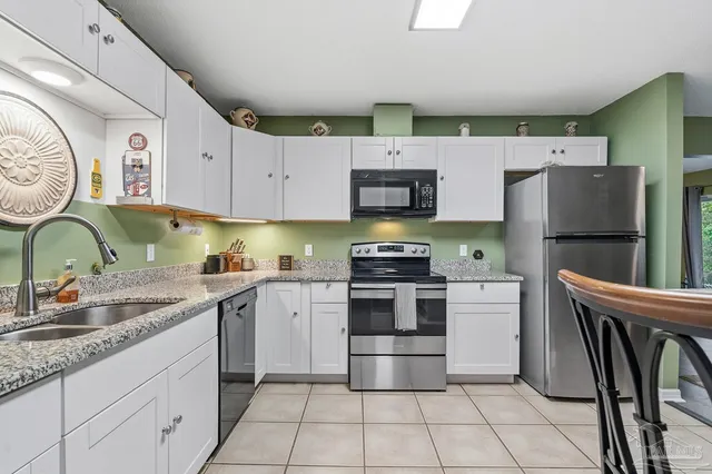 a large kitchen with granite countertop a sink a stove top oven and cabinets