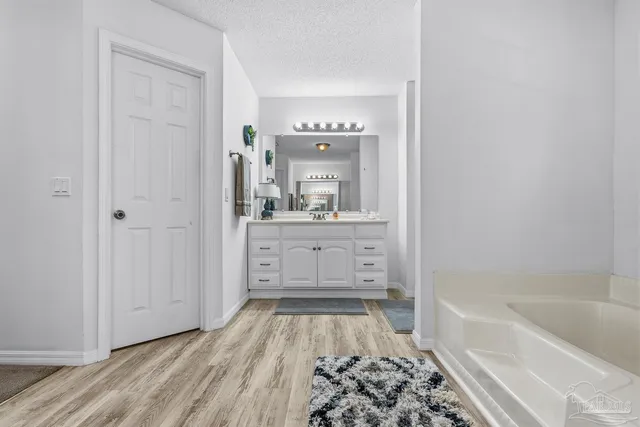 a spacious bathroom with a tub sink and a mirror