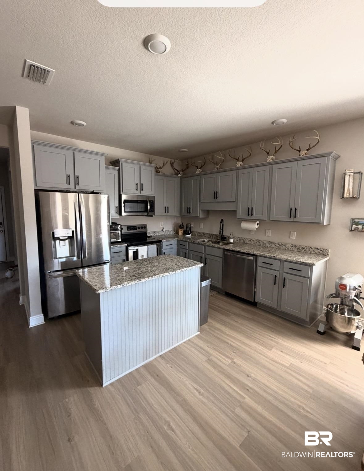 32215 Calder Court Daphne, AL 36527 - Photo 5 of 13 Kitchen with gray cabinetry, stainless steel appliances, light stone counters, a center island, and light wood finished floors