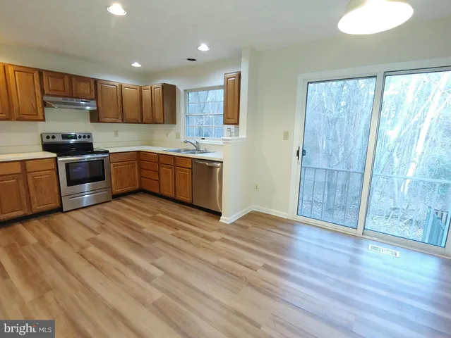 a large kitchen with stainless steel appliances granite countertop a stove a sink dishwasher and a refrigerator with wooden floor