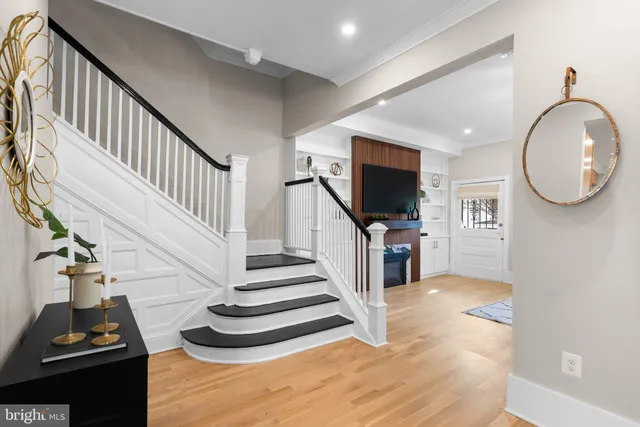 a living room with couches a dining table and a chandelier with wooden floor