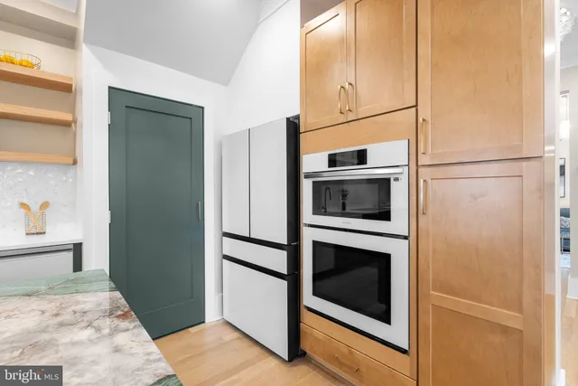 a kitchen with stainless steel appliances granite countertop a sink a stove a refrigerator and a dining table with wooden floor