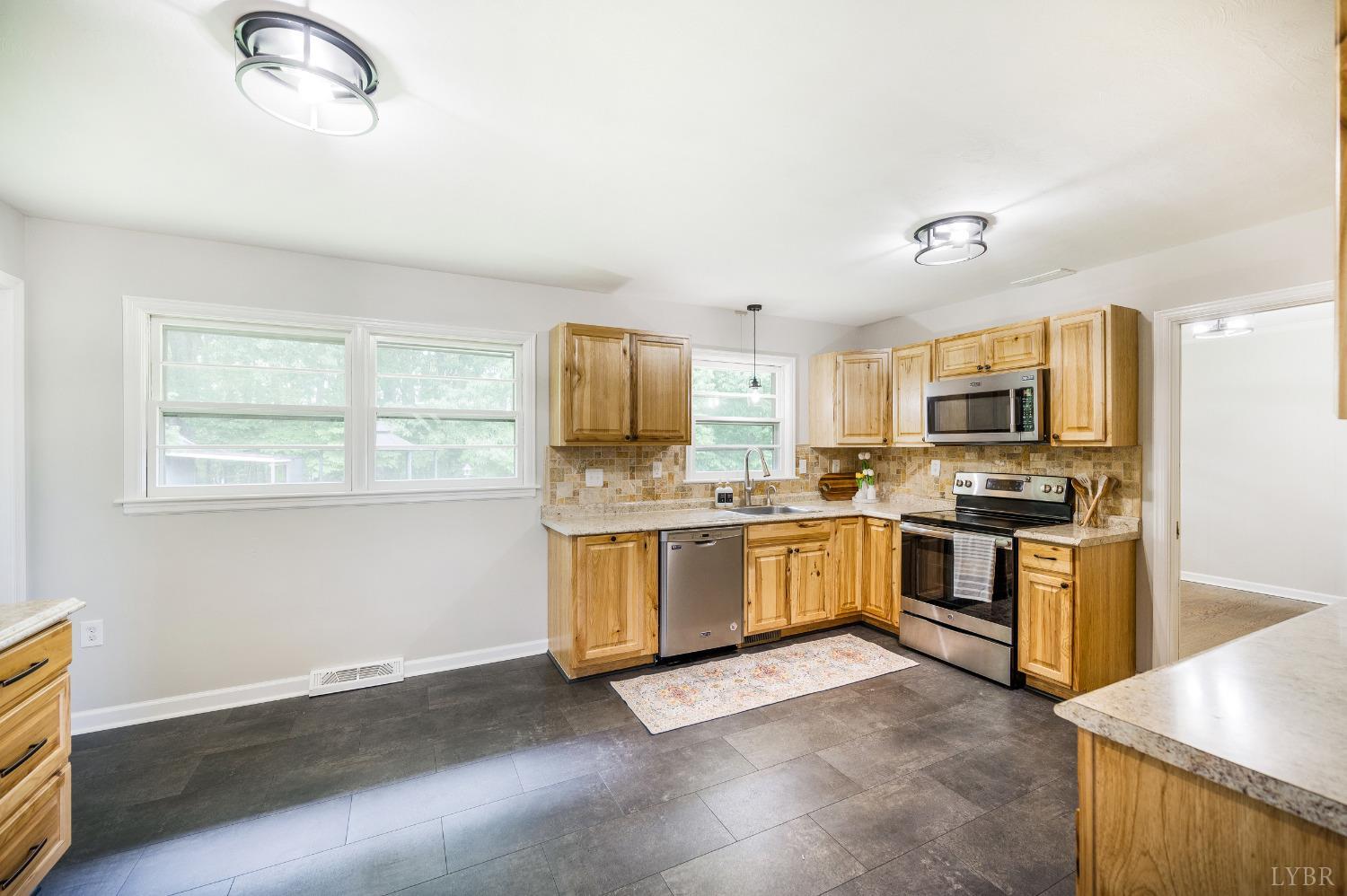 7230 Wards Road Rustburg, VA 24588 - Photo 16 of 58 a open kitchen with granite countertop a stove top oven a sink dishwasher a dining table and chairs with wooden floor
