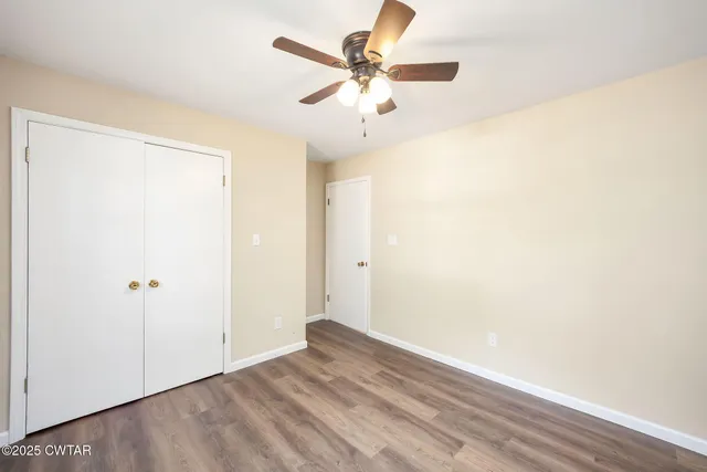 a view of an empty room with wooden floor and cabinets