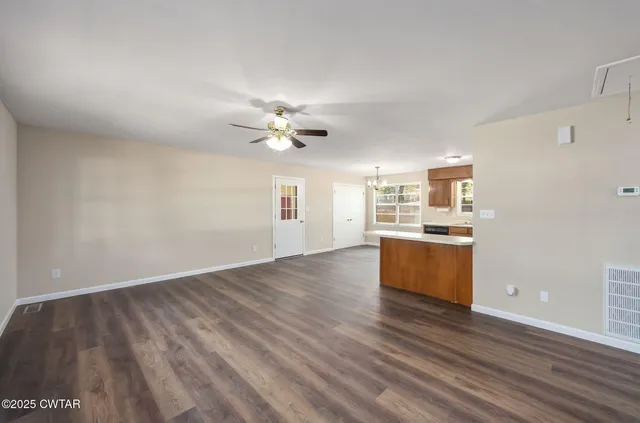 an empty room with wooden floor fireplace and windows