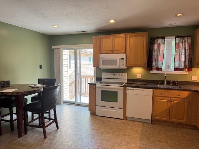 14 Moss Street, Unit 2 Burlington, MA 01803 - Photo 4 of 22 a kitchen with a stove a sink a microwave a dining table and chairs