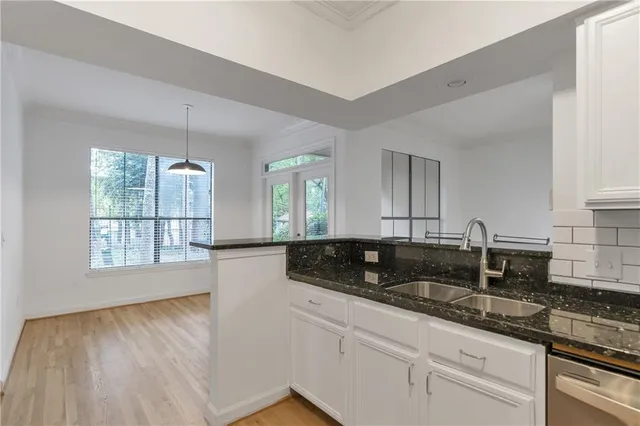 a kitchen with granite countertop a sink and white cabinets