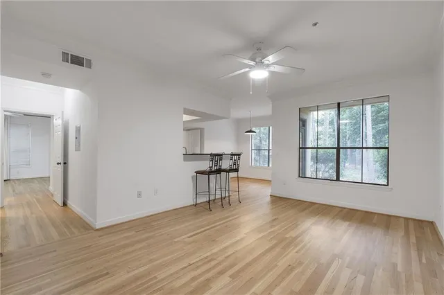 a view of empty room with wooden floor and fan