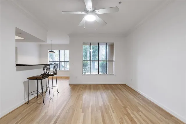 an empty room with wooden floor fan and windows