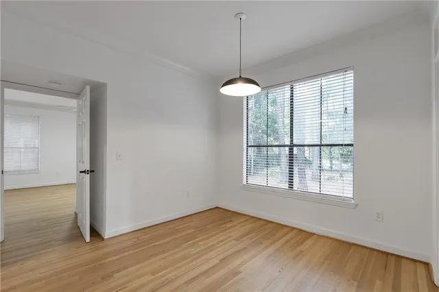 a view of an empty room with wooden floor and a window