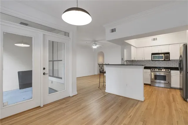 a view of kitchen with granite countertop stainless steel appliances and wooden floor