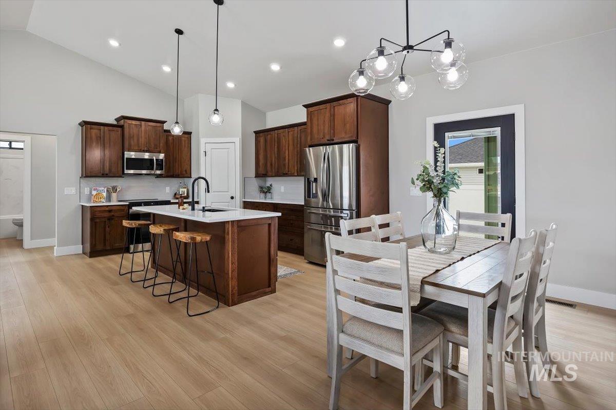 1201 Jade Drive Rupert, ID 83350 - Photo 7 of 27 Open-concept kitchen and dining area featuring warm wood cabinetry, stainless steel appliances, and a central island with counter seating
