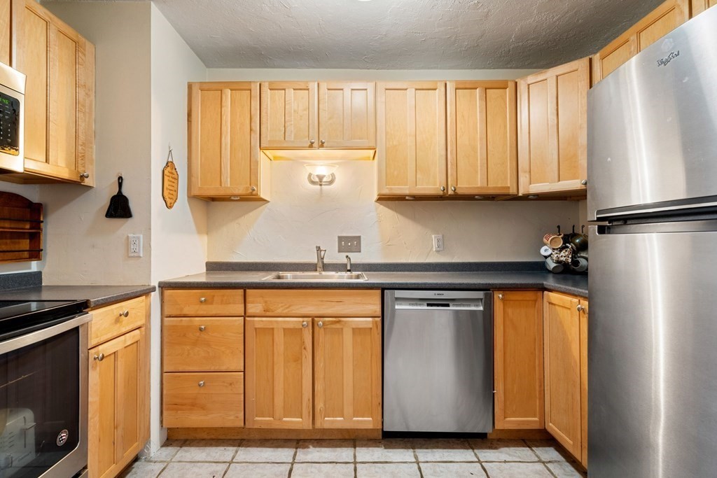 474 Broadway, Unit 49 Somerville, MA 02145 - Photo 5 of 19 a kitchen with stainless steel appliances granite countertop a refrigerator a sink and white cabinets
