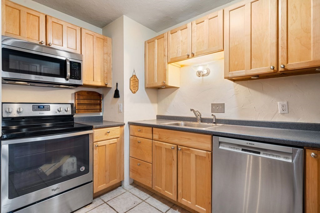 474 Broadway, Unit 49 Somerville, MA 02145 - Photo 7 of 19 a kitchen with stainless steel appliances granite countertop white cabinets a sink and dishwasher