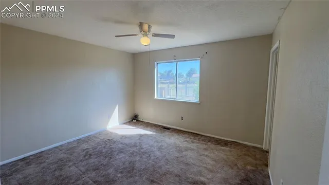 an empty room with windows and fan
