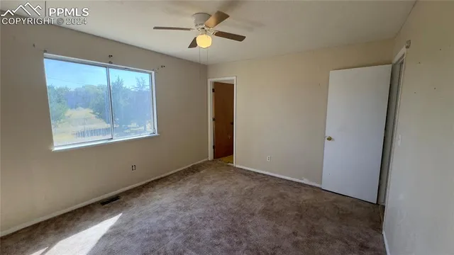 an empty room with windows and chandelier fan