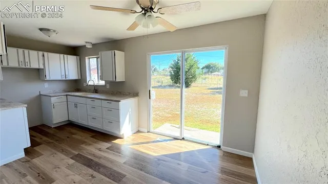 a kitchen with granite countertop a stove a sink and white cabinets with wooden floor next to windows
