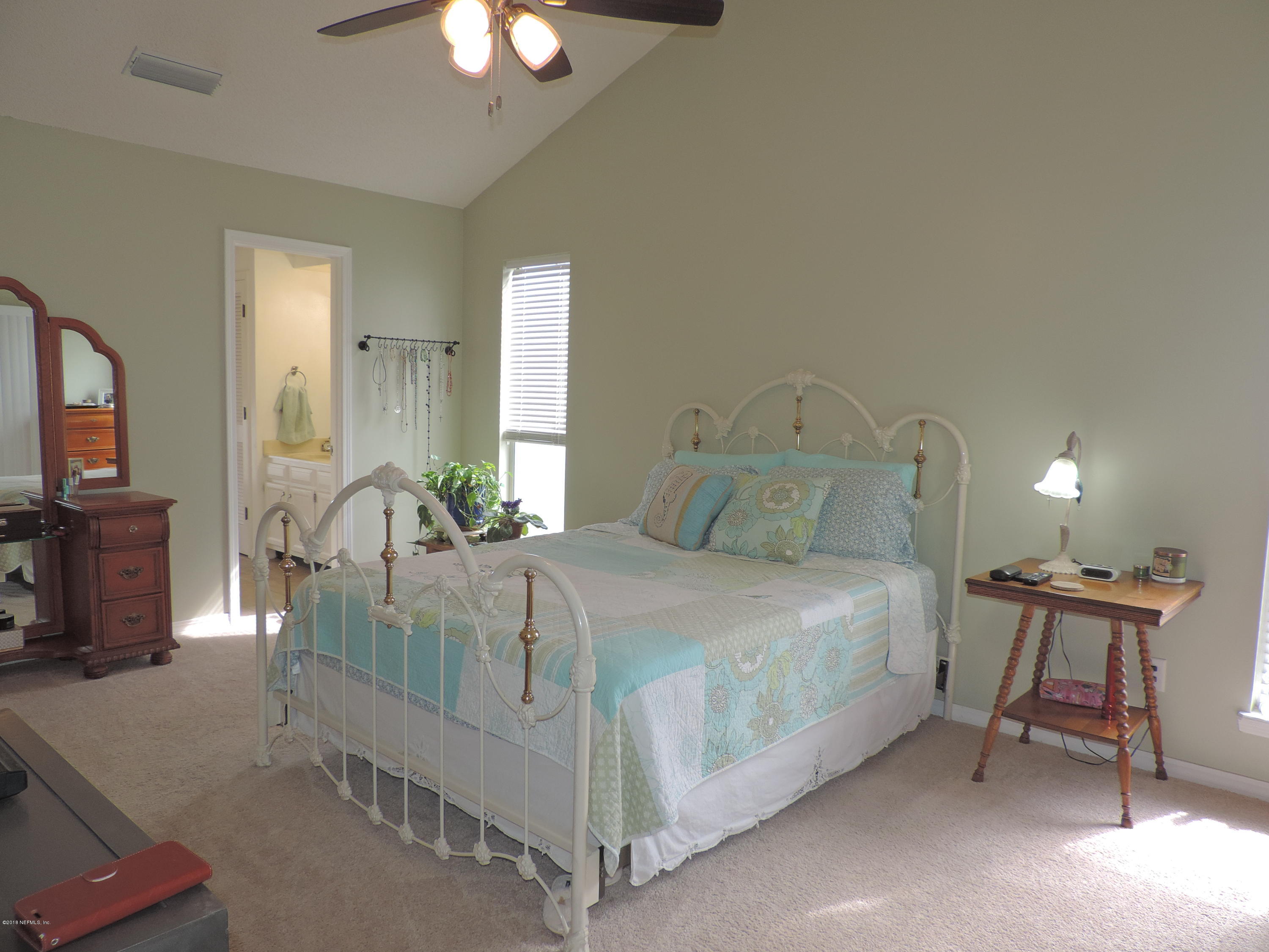 7024 St Augustine Road Jacksonville, FL 32217 - Photo 14 of 34 a bedroom with a bed a mirror on dresser and a chandelier