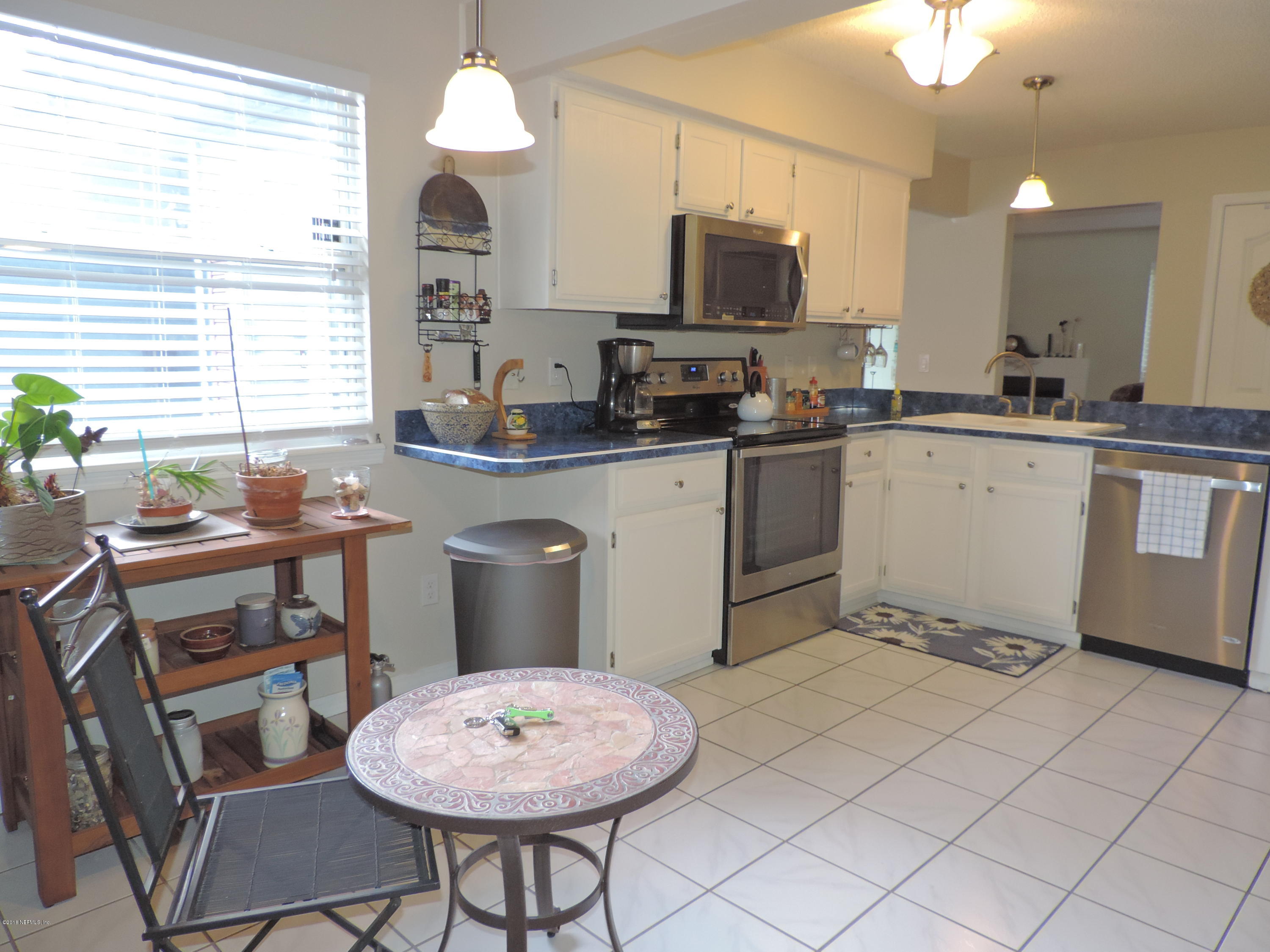 7024 St Augustine Road Jacksonville, FL 32217 - Photo 24 of 34 a kitchen with a stove a sink cabinets and a dining table