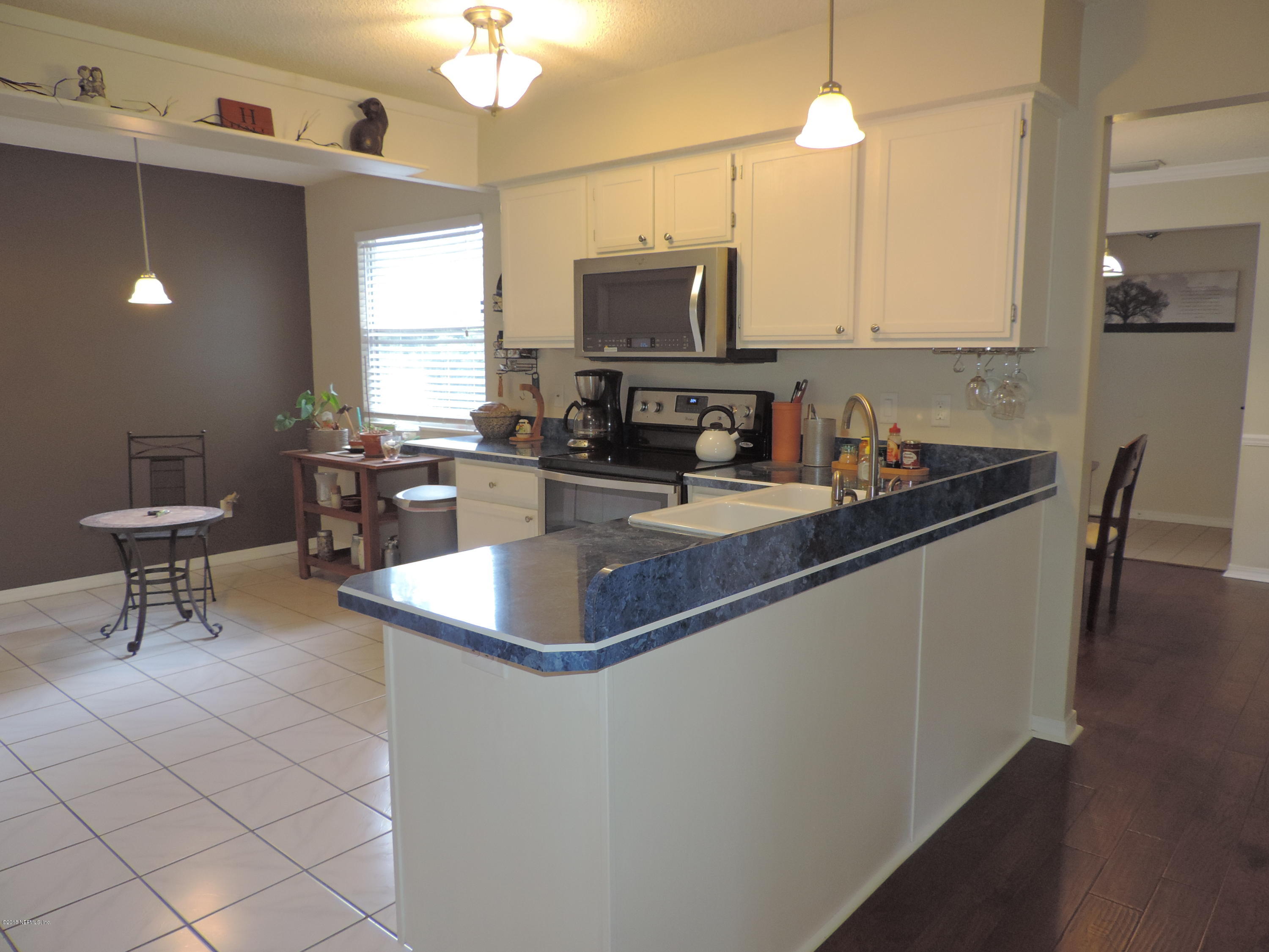 7024 St Augustine Road Jacksonville, FL 32217 - Photo 27 of 34 a kitchen with kitchen island granite countertop a sink a counter top space appliances and cabinets