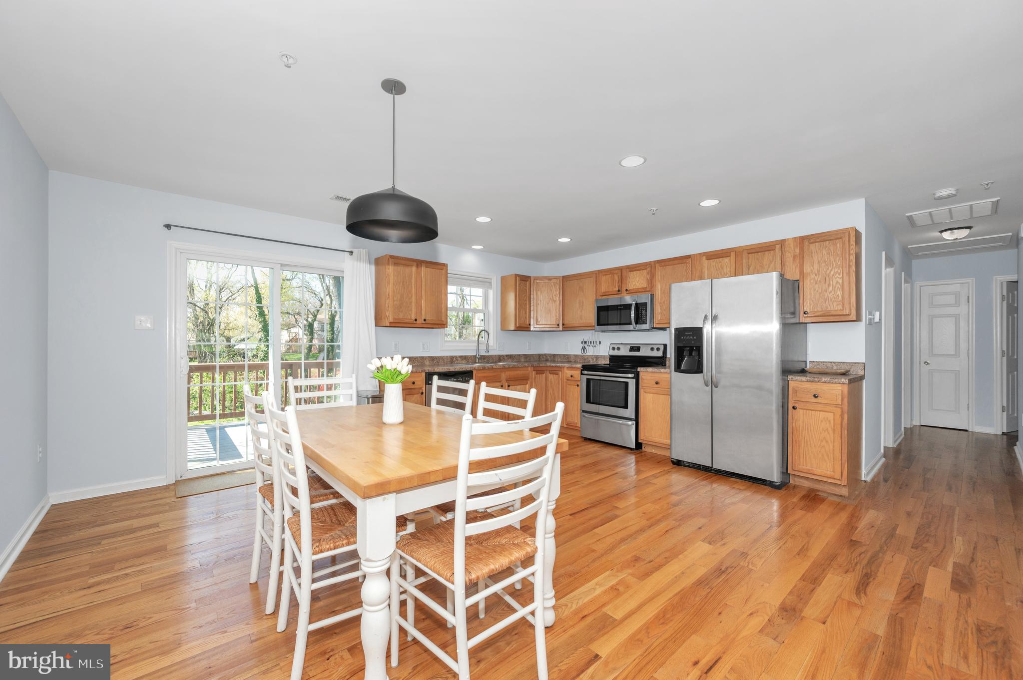 1107 2nd Avenue Brunswick, MD 21716 - Photo 11 of 52 a kitchen with stainless steel appliances granite countertop a dining table chairs refrigerator and wooden floor