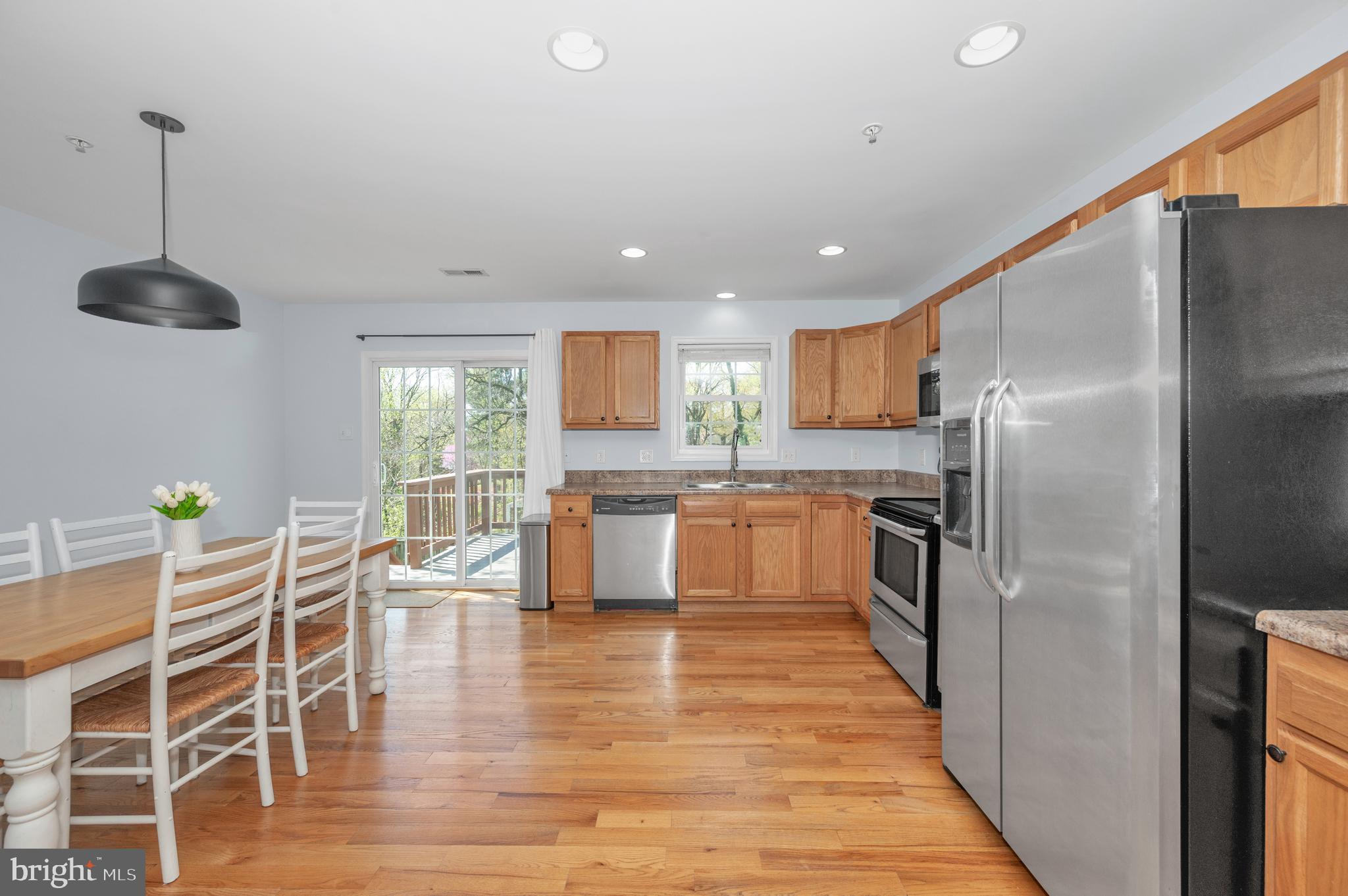 1107 2nd Avenue Brunswick, MD 21716 - Photo 14 of 52 a kitchen with stainless steel appliances granite countertop a refrigerator a stove top oven a sink dishwasher a dining table and chairs with wooden floor