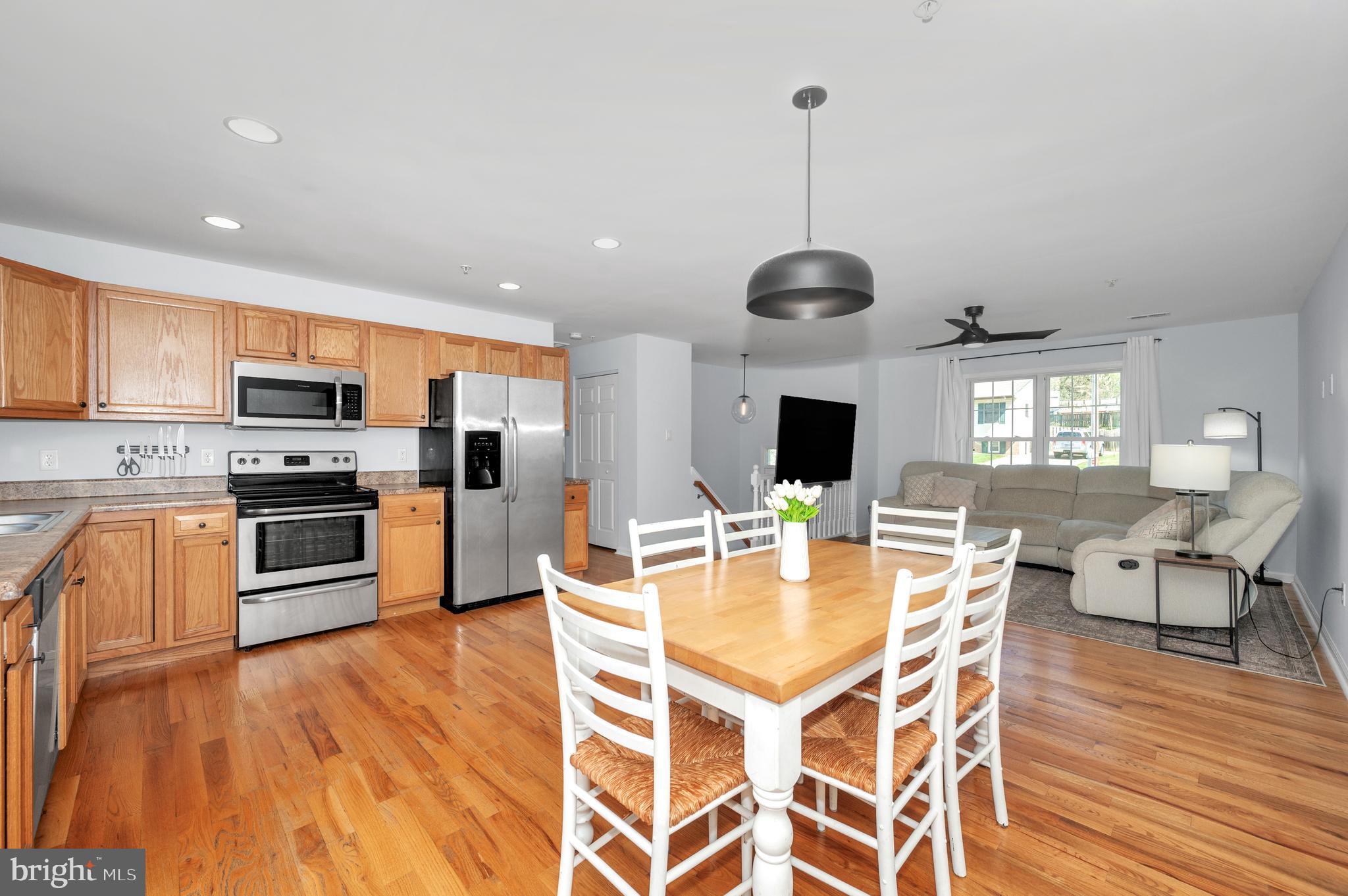 1107 2nd Avenue Brunswick, MD 21716 - Photo 10 of 52 a kitchen with stainless steel appliances granite countertop a stove top oven a refrigerator a sink dishwasher a dining table and chairs with wooden floor