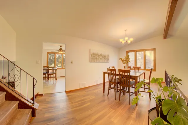 a dining room with furniture floor to ceiling windows and wooden floor