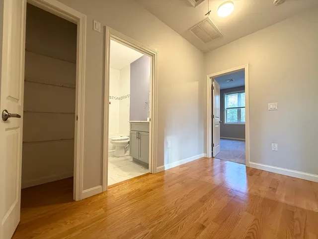 a view of a hallway with wooden floor and a bathroom