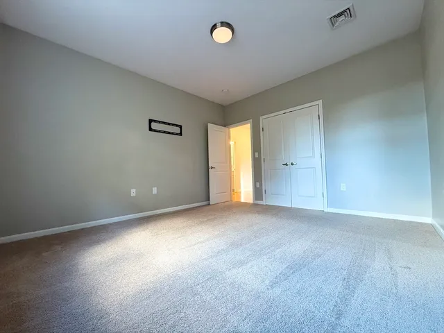 a view of an empty room with a window and a kitchen
