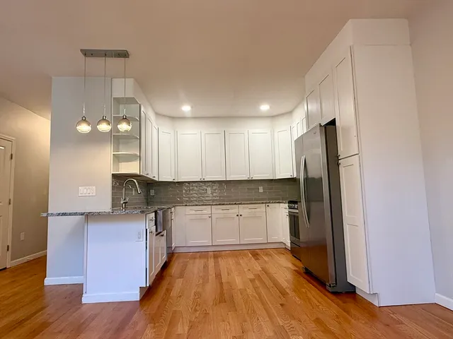 a large kitchen with a sink stainless steel appliances and wooden floor